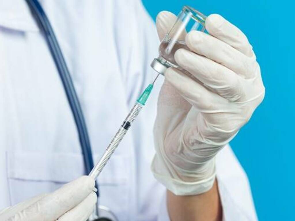 close up picture of docter's  hands holding hypodermic syringe